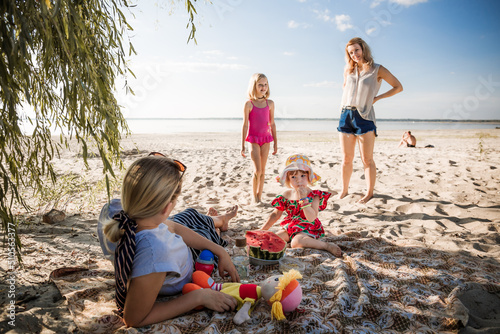 Cuadro en lienzo Young happy mothers with their children are resting on the beach