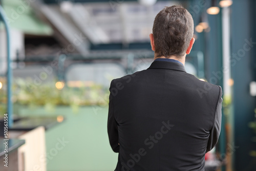 Rear view portrait of caucasian businessman in suit standing and arms cross with confident while looking camera with happy face in modern office. Success business concept.