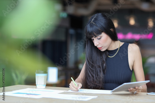 Portrait of confident African businesswoman with happy smiling emotion drinking coffee while sitting and using tablet and smart mobile phone on table in restaurant. Success business concept