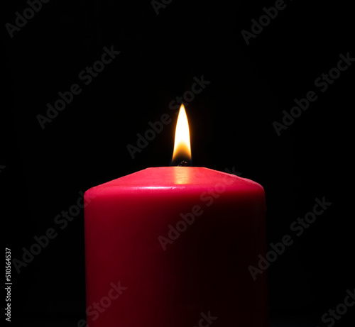 Burning red candle on black