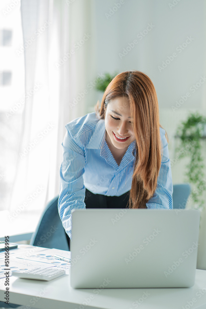 Asian businesswoman working on laptop computer in office with documents on desk woman looking at financial statistics data analysis chart profit growth business idea vertical image Asian businesswoman working on laptop computer in office with documents on desk woman looking at financial statistics data analysis chart profit growth business idea vertical image