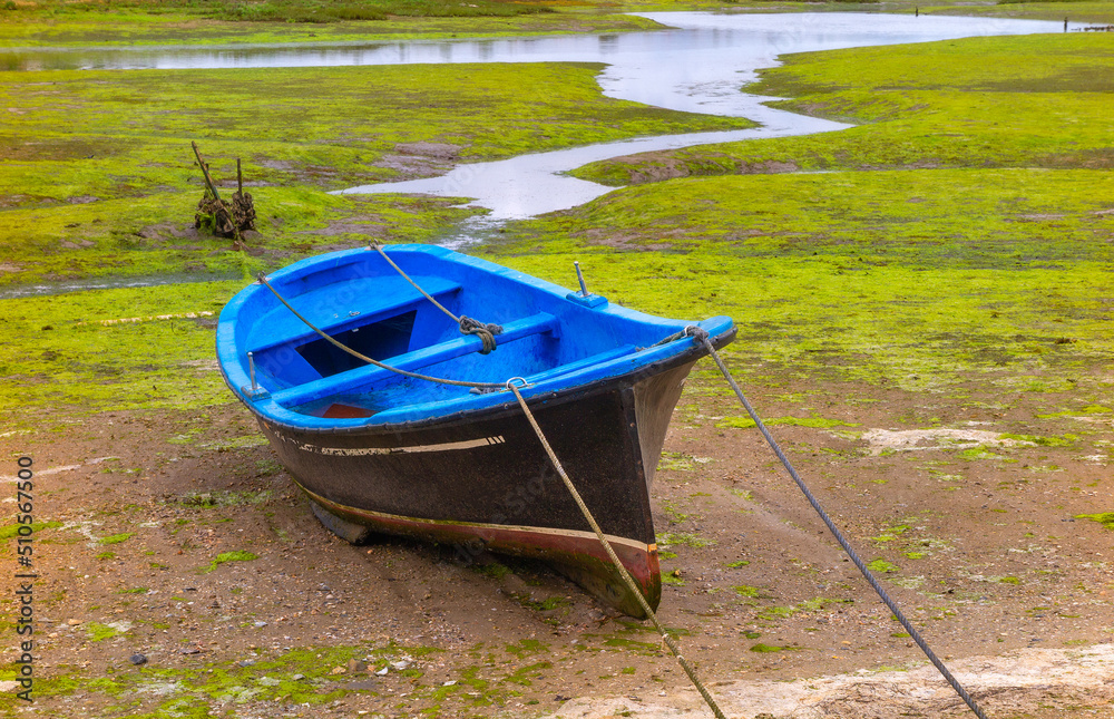 small fishing boat moored in the mudflat at low tide