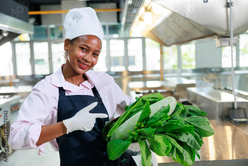 portrait young teen girl cook student. Cooking class. culinary classroom. happy young african woman students holding fresh vegetables for cooking in cooking school.