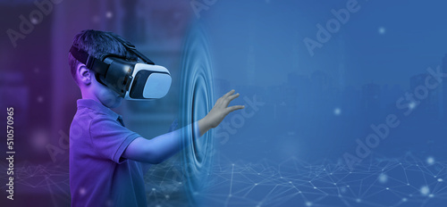 Boy with VR glasses from his room touches the metaverse with his hand. Copy space on blue background photo