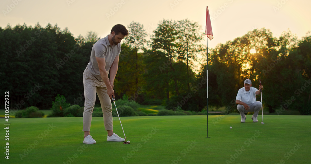 Obraz premium Sport men play golf game on field. Golfing team spend time on luxury resort.