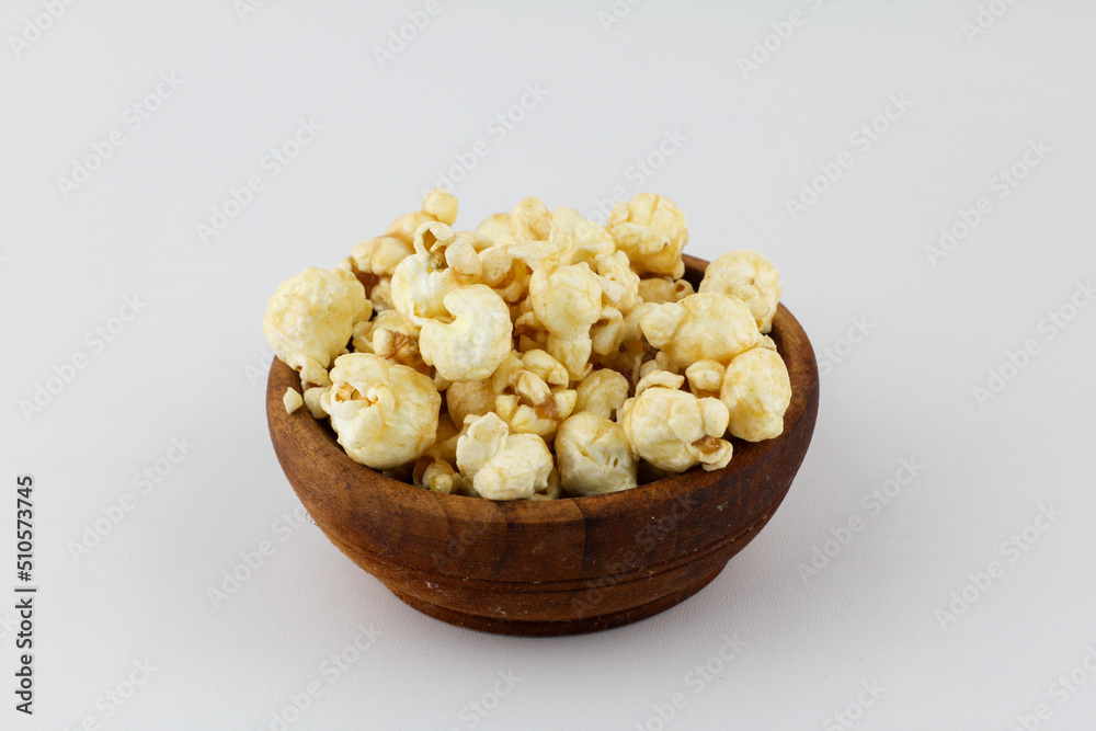 Caramel popcorn on wooden bow white background Caramel popcorn on wooden bow white background