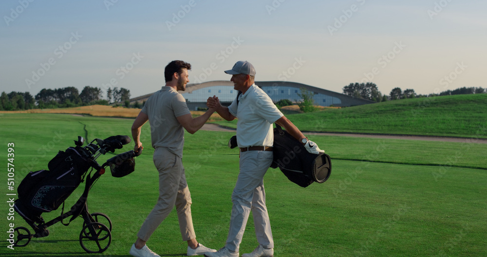 Golf players shaking hands on grass field. Two friends meeting play on weekend. Golf players shaking hands on grass field. Two friends meeting play on weekend.