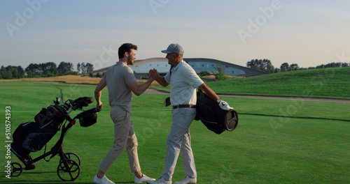 Golf players shaking hands on grass field. Two friends meeting play on weekend.