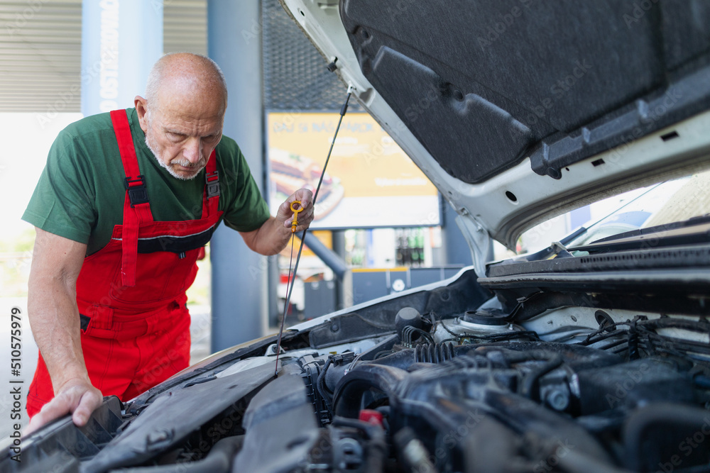 Senior mechanic checking the oil level in the car engine. Senior mechanic checking the oil level in the car engine.