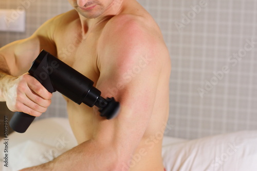 Sportsman with massage gun at home,