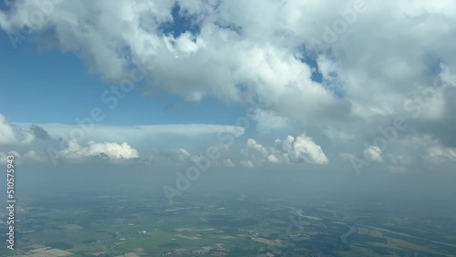 Aerial cockpit view, pilot pov, from a jet cockpit during a left turn near Milan (Italy) airport, with a partially cloudy sky and deep blue heaven photo