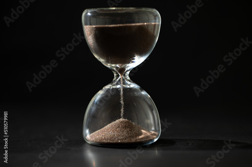 hourglass (sand clock) on a black background, Hourglass as time passing concept for business deadline, Life-time passing concept, with copy space