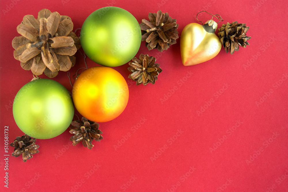 Green, yellow Christmas balls, cones and decorative baubles, on a red background
