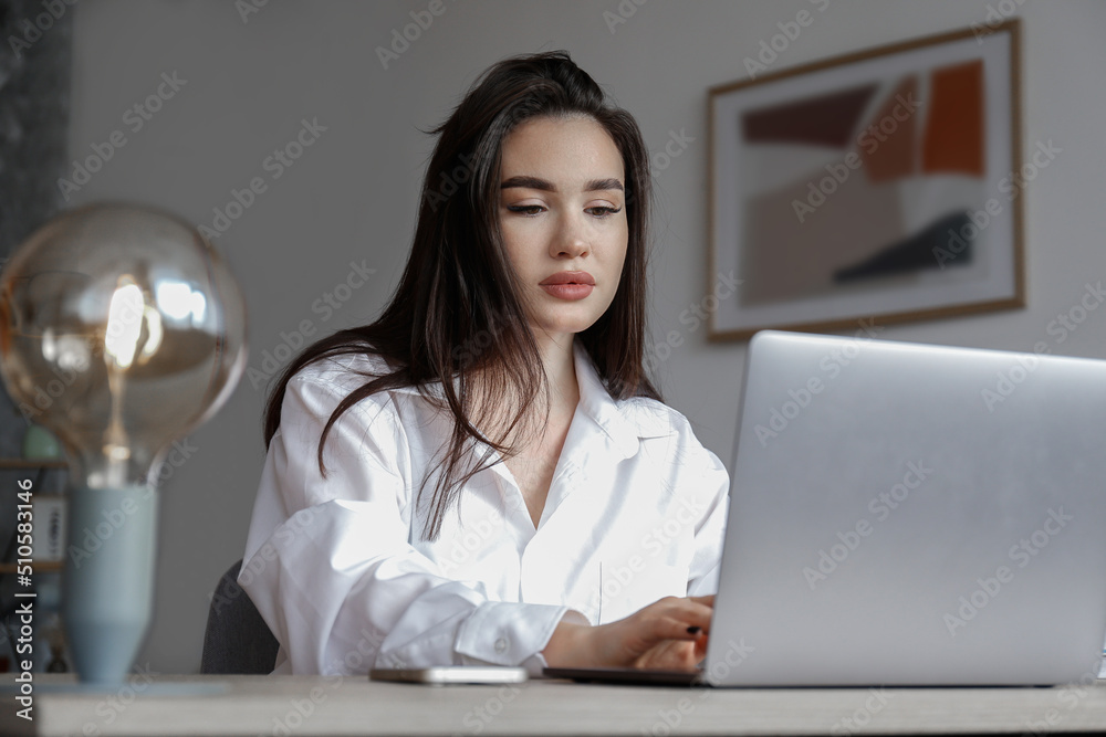 Young beautiful brunette woman at the office, copywriter typing a new text on her laptop. Portrait of female busy at her workplace, dived deep into the work. Close up, copy space, background. Young beautiful brunette woman at the office, copywriter typing a new text on her laptop. Portrait of female busy at her workplace, dived deep into the work. Close up, copy space, background.