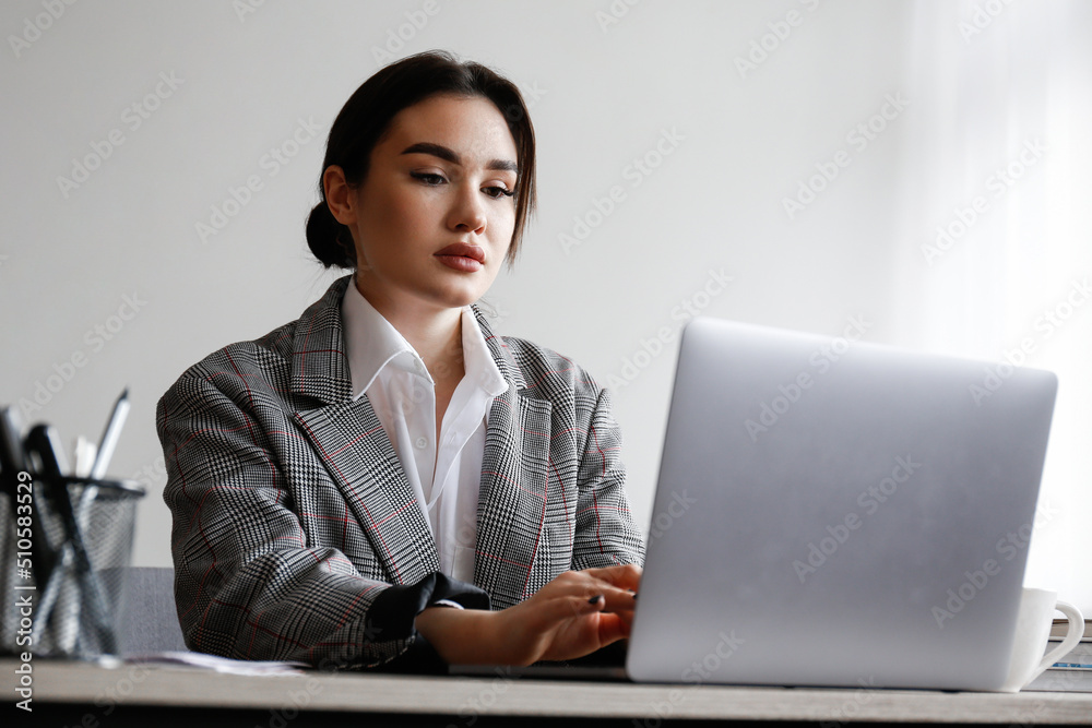 Young beautiful brunette woman at the office, copywriter typing a new text on her laptop. Portrait of female busy at her workplace, dived deep into the work. Close up, copy space, background. Young beautiful brunette woman at the office, copywriter typing a new text on her laptop. Portrait of female busy at her workplace, dived deep into the work. Close up, copy space, background.