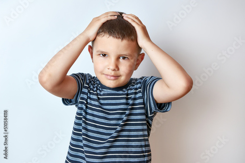 A handsome boy holds his hands behind his head.