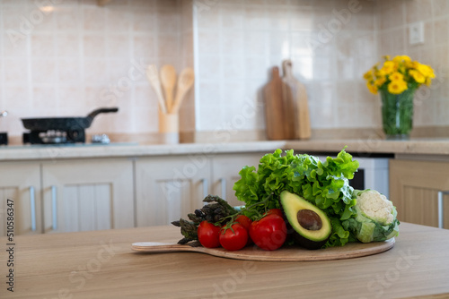 Bunch of different raw organic fruits, vegetables and greens lying in pile on a chopping board. Kitchen table with groceries. Close up, copy space for text, interior background.