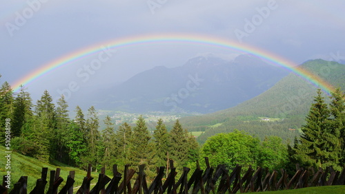 Halbkreisförmiger Regenbogen in einem Bergtal