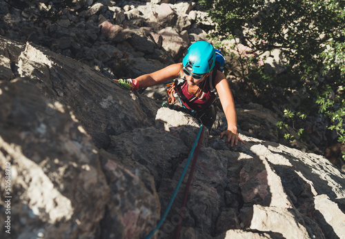 Active Woman in protective helmet and sunglasses on cliff rock wall lead climbing using rope and climbing harness in Paklenica National park, Croatia. Active extreme sports time spending concept photo