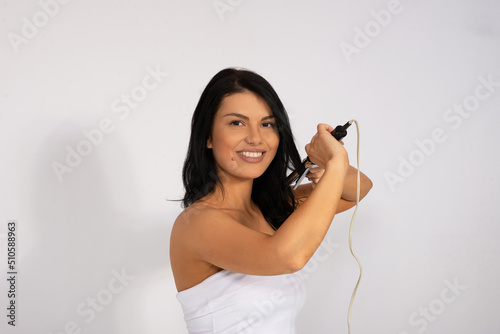caucasian woman with hair iron curler , hair care and hairstyle concept studio shot