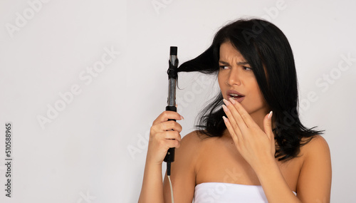 caucasian woman with hair iron curler , hair care and hairstyle concept studio shot