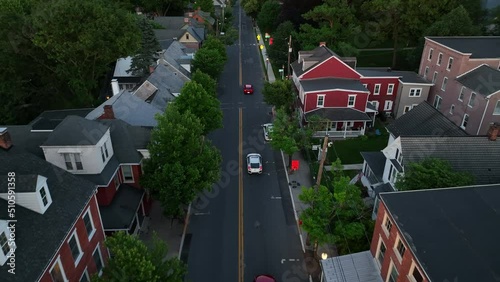 Aerial tracking shot of Honda Civic sedan. Cars drive in small town America at dusk during spring.