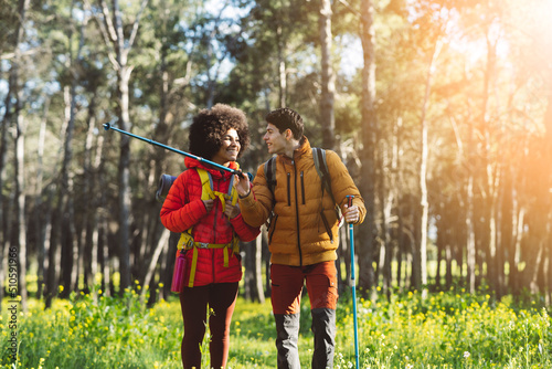 Foto happy multiracial couple trekking in nature at sunset - backpacker travelers -