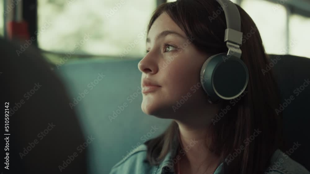 Girl teenager traveling bus with headphones close up. Brunette listening music.