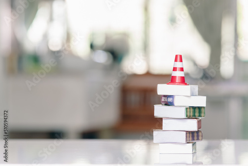 Fotografie Effective safety training and refresher training concept : White-orange traffic cone, safety or a road cone on a row of books, depicting the study focused on developing solutions to improve safety