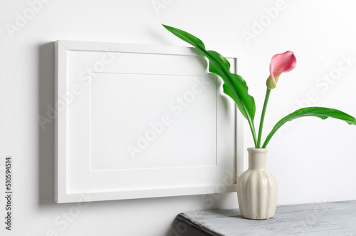 Landscape blank frame mockup with calla flowers over white wall