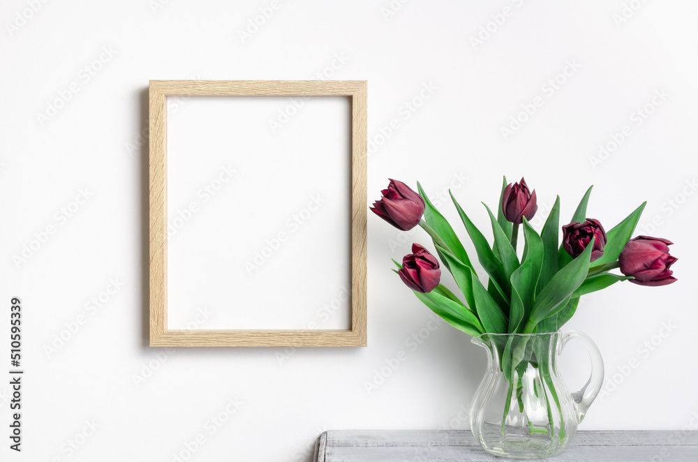 Wooden portrait frame mockup with tulips flowers over white wall Wooden portrait frame mockup with tulips flowers over white wall