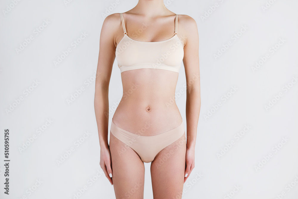 Close up shot of unrecognizable fit woman in lingerie isolated on white background. Torso of slim attractive female with flat belly in beige underwear. Copy space for text. Close up shot of unrecognizable fit woman in lingerie isolated on white background. Torso of slim attractive female with flat belly in beige underwear. Copy space for text.
