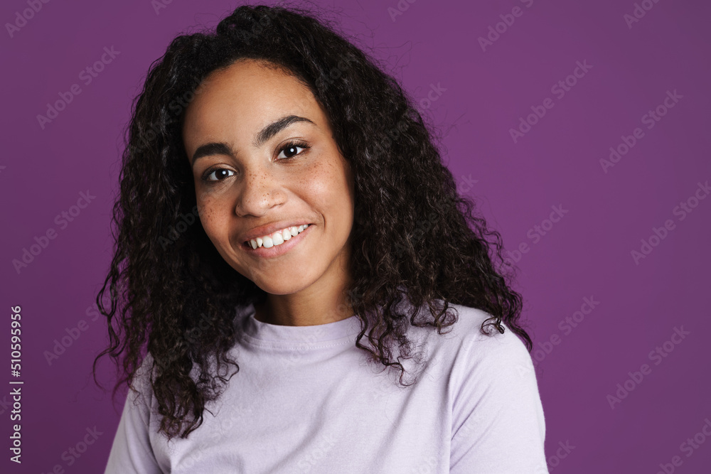 Young black woman with wavy hair smiling and looking at camera Young black woman with wavy hair smiling and looking at camera