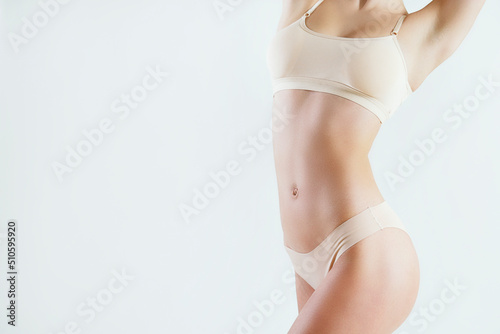 Cropped shot of unrecognizable fit woman in lingerie isolated on white background. Torso of slim attractive female with flat belly in white underwear. Copy space for text, close up.