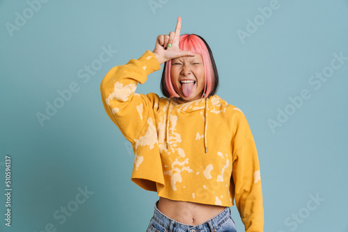 Asian girl showing her tongue and pointing finger upward