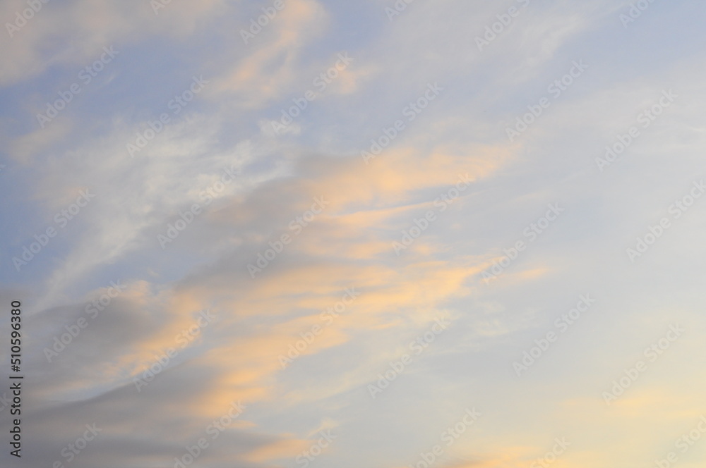 Background of evening sky, light stretched clouds in the sun. Sky with a gradient of color from warm to cold