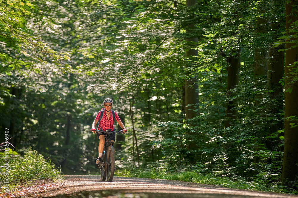 Obraz premium nice active senior woman riding her electric mountain bike in the green city forest of Stuttgart, Germany