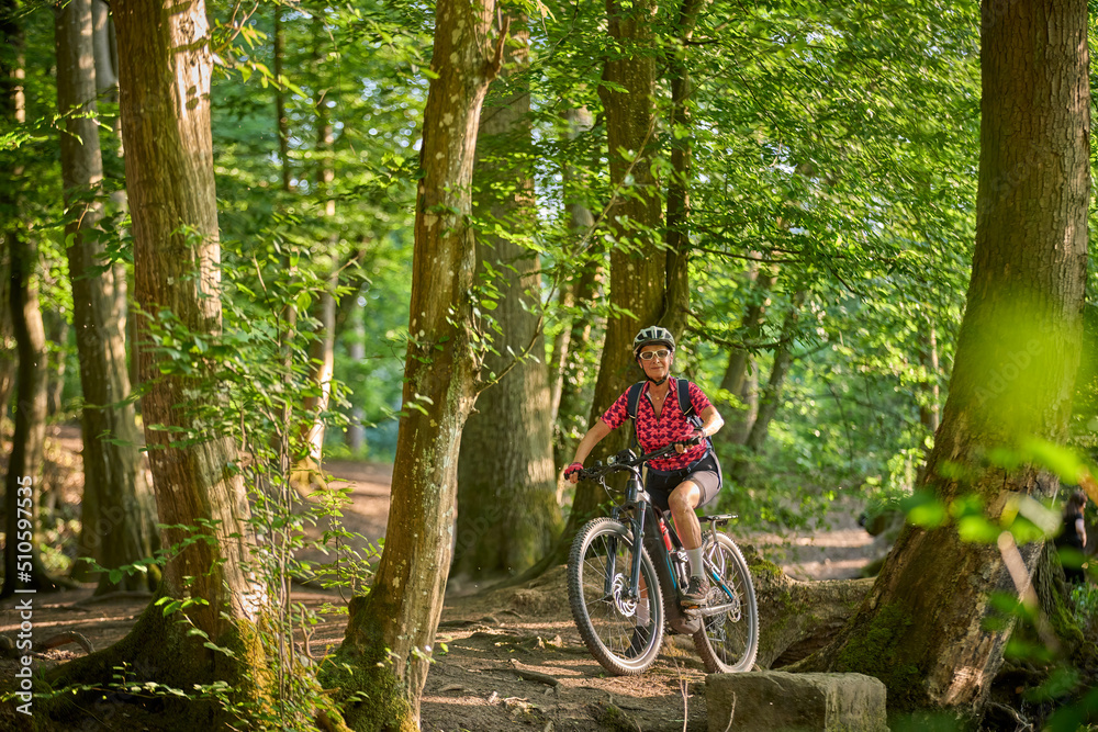 nice active senior woman riding her electric mountain bike in the green city forest of Stuttgart, Germany
