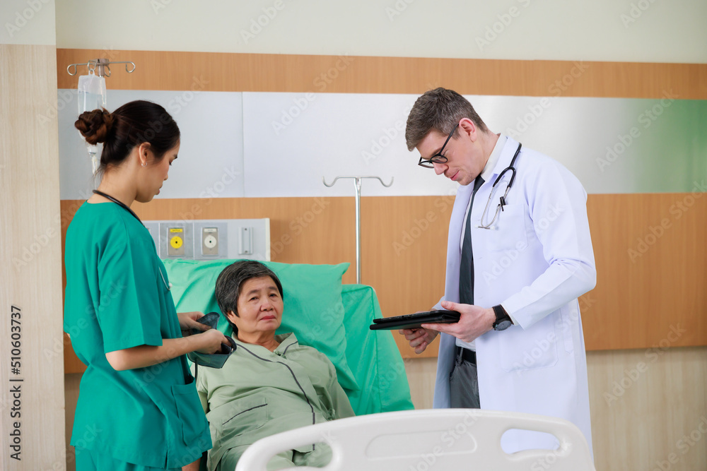 Fototapeta premium Elderly woman patient on hospital bed and man doctor with nurse. doctor talking consulting and checkup by stethoscope with patient. Hospital Healthcare and medicine concept.