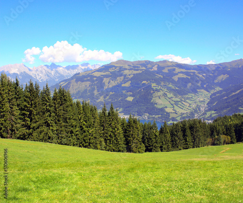 Alps mountains in Tirol, Austria. Aerial view of idyllic mountain scenery in Alps with green grass and fur-trees on sunny day