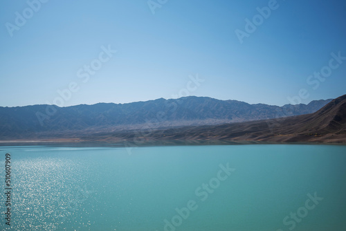Lake with mountains on the background. Mountain range view. A sultry haze over desert mountains and a salty turquoise lake. © eskstock