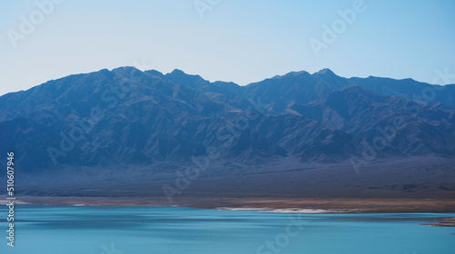 Lake with mountains on the background. Mountain range view. A sultry haze over desert mountains and a salty turquoise lake.