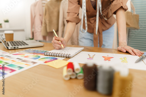 Fashion design concept, Asian female fashion designer sketching new clothes collection in atelier