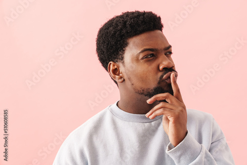 Black puzzled man with beard posing and looking aside