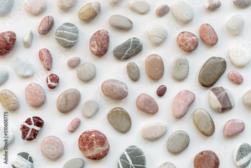 Top view close up sea stones on light background. Colorful pebbles as summer pattern. Natural stone white red pink grey colors. Minimal flat lay, background with natural materials