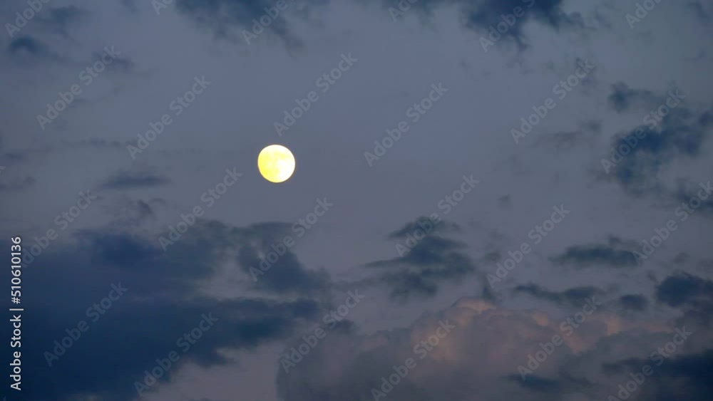 Clouds float across the evening sky with a full moon Clouds float across the evening sky with a full moon