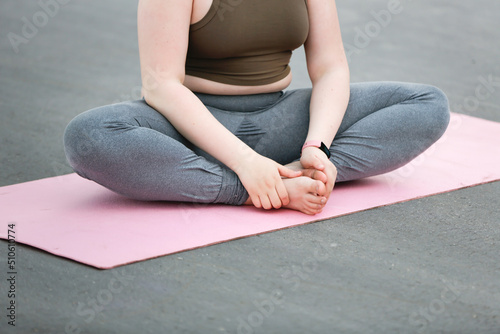 Plus size girl teenager meditates on yoga mat outside in summer, excess weight in teenagers, calmness and yoga classes