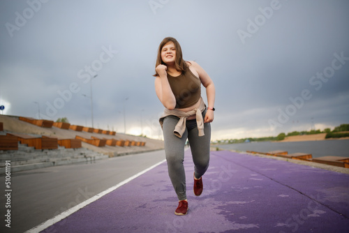 European teenage girl overweight on jog on treadmill along embankment of city  overweight and active lifestyle of teenager