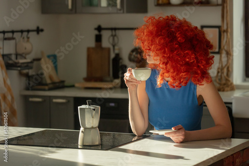 Redhead woman with cup of coffee in kitchen at home