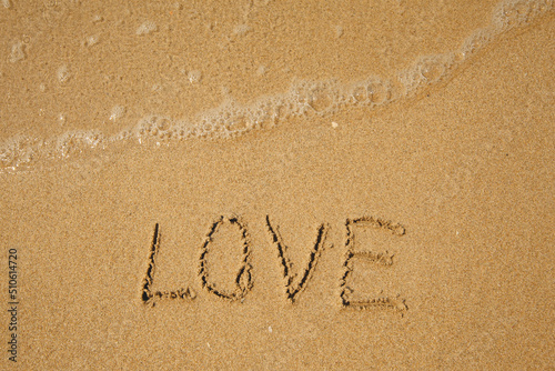 LOVE - handwritten on the soft beach sand.